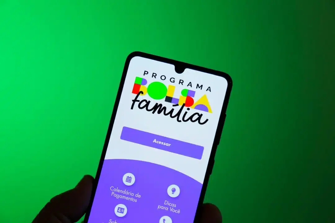 Cart&atilde;o do programa Bolsa Fam&iacute;lia sendo segurado por uma m&atilde;o.