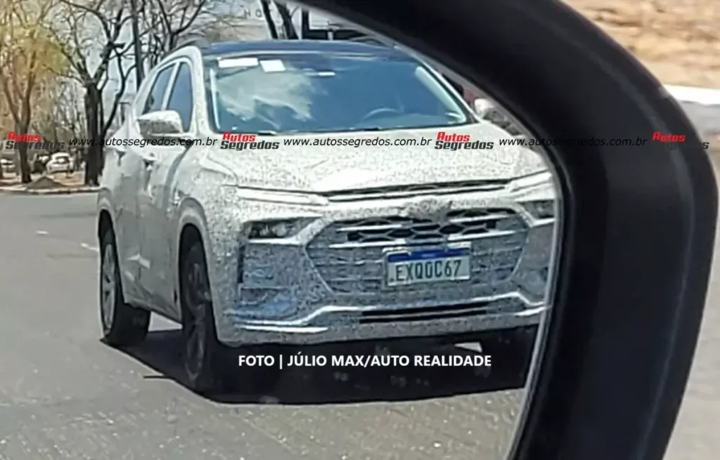 Flagra do Chevrolet Tracker 2026 Híbrido visto através do espelho retrovisor.