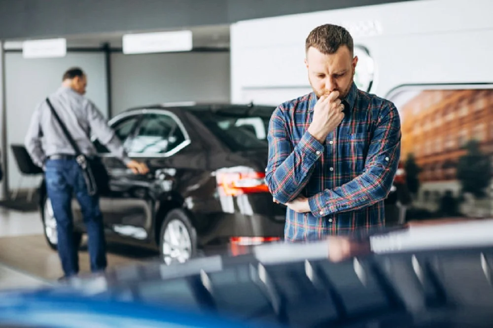 Homem jovem escolhendo carro em um showroom.