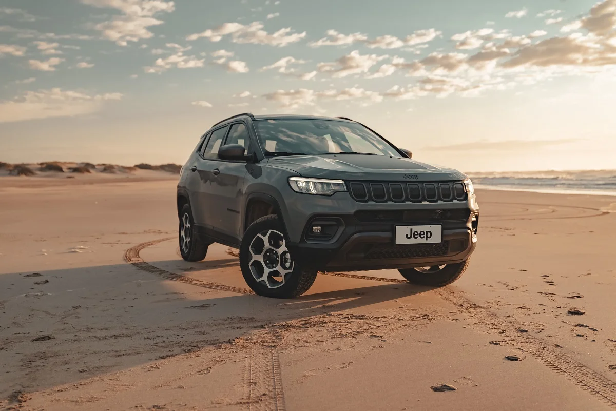 Jeep Compass estacionado na praia com o mar ao fundo
