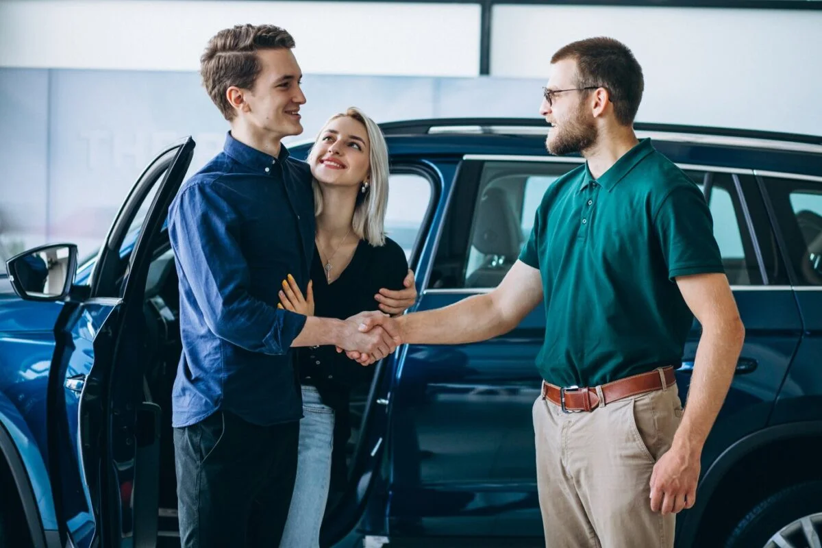 Pessoa cumprimentando um vendedor ao comprar um carro.