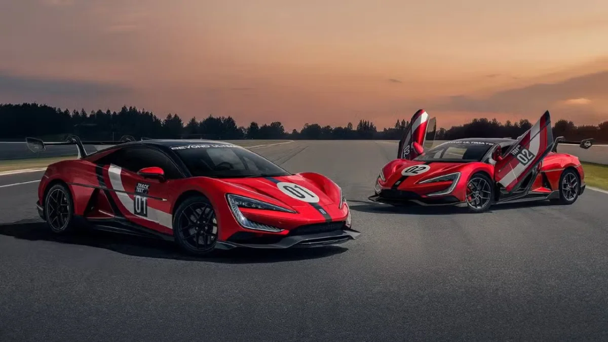 Dois carros esportivos em uma pista durante o pôr do sol.