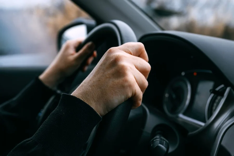 Mãos segurando o volante de um carro.