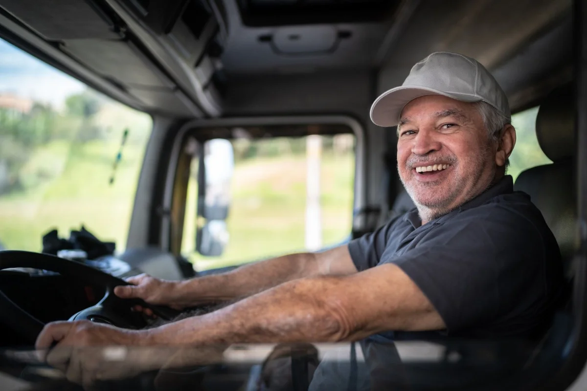 Motorista ao volante sorrindo, representando segurança no trânsito