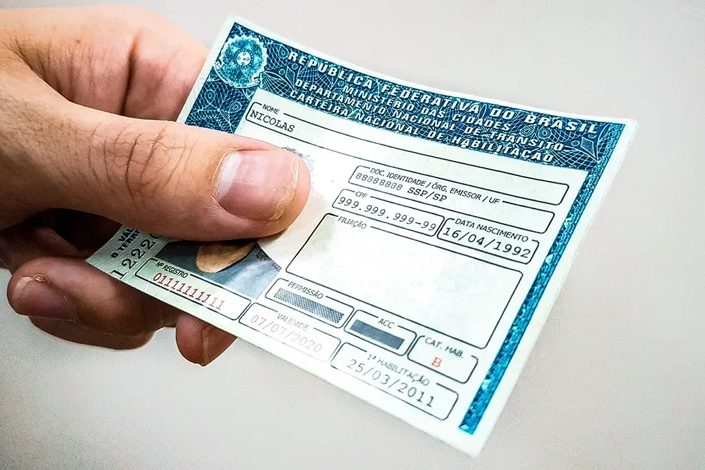 Imagem de uma CNH sendo retirada de uma carteira.