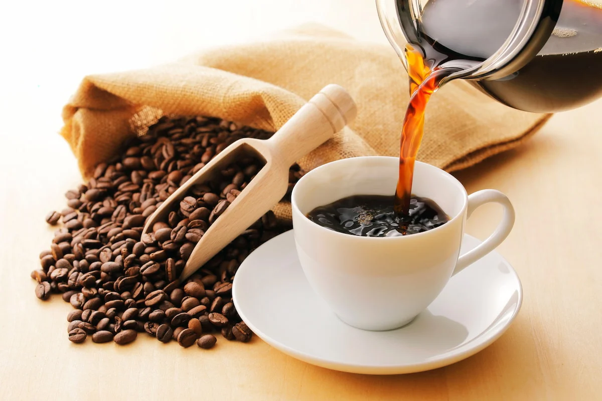 Xícara de café com grãos ao fundo