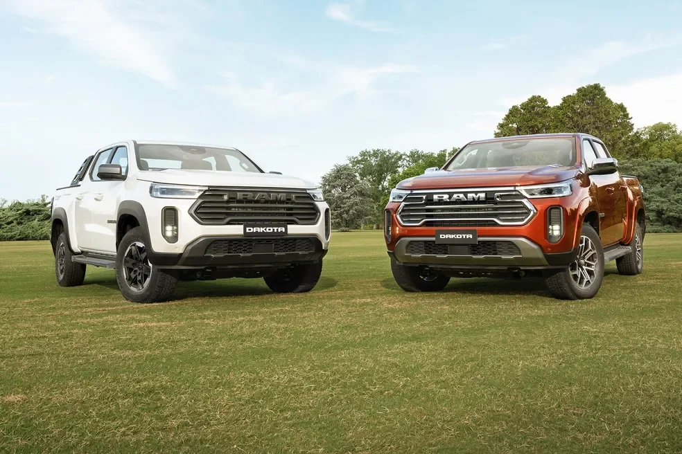 As vers&otilde;es da Ram Dakota Laramie 2026 est&aacute;ticas em um campo gramado.