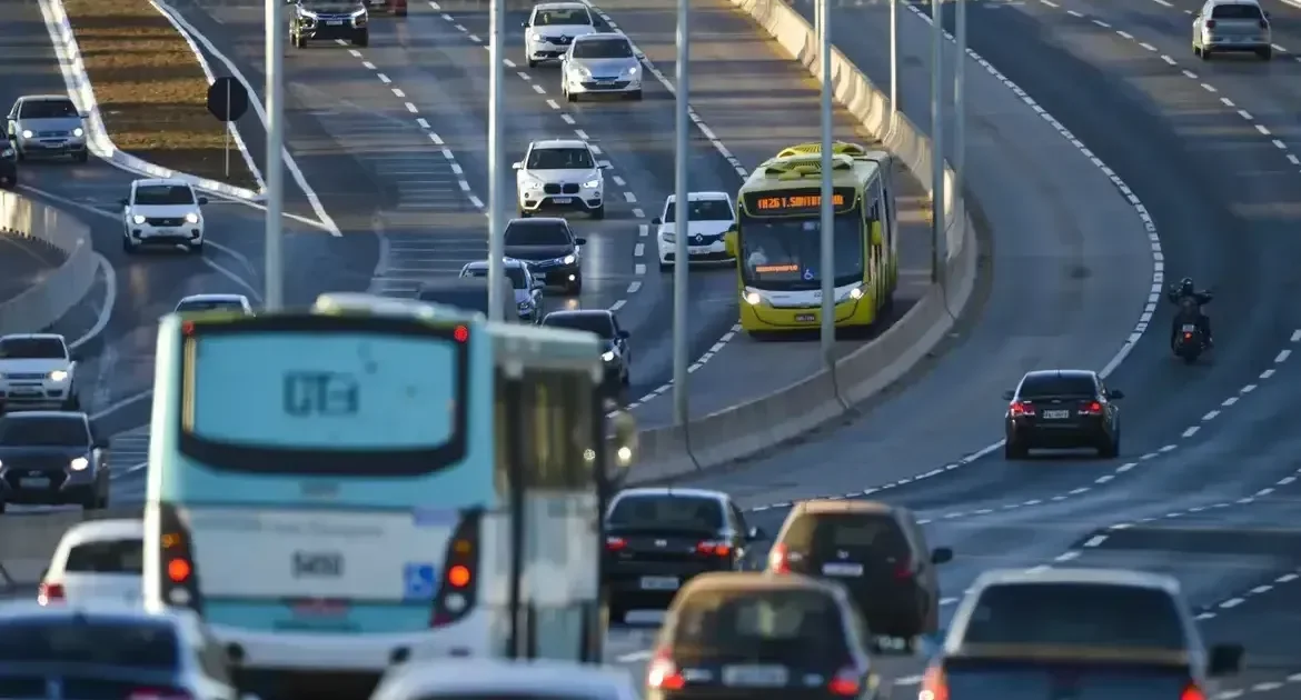 Ve&iacute;culos e &ocirc;nibus em uma avenida movimentada.