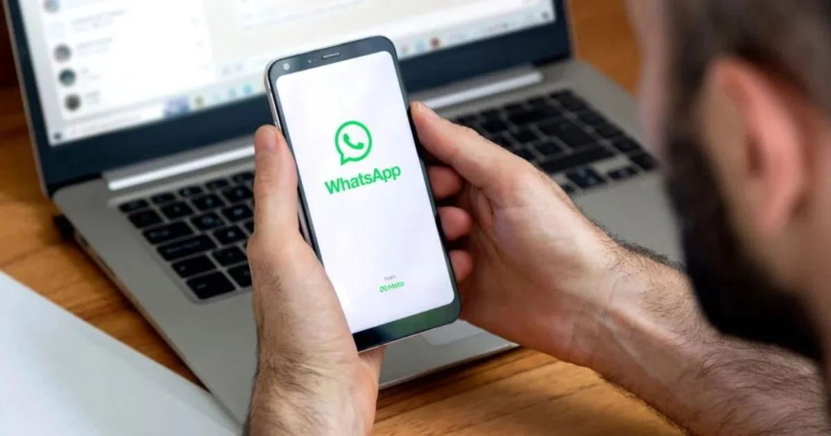 Pessoa segurando um smartphone com o aplicativo WhatsApp na tela.