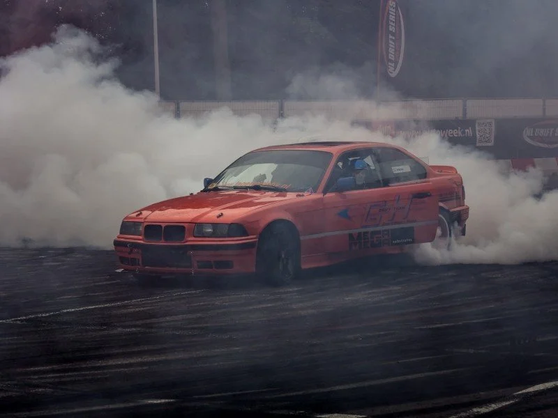 Carro em alta velocidade fazendo drift com fumaça dos pneus.