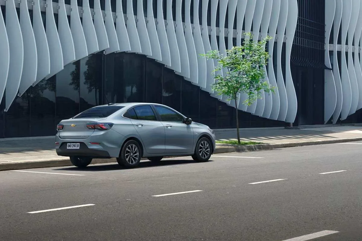 Chevrolet Onix Plus estacionado em frente a um edifício moderno.