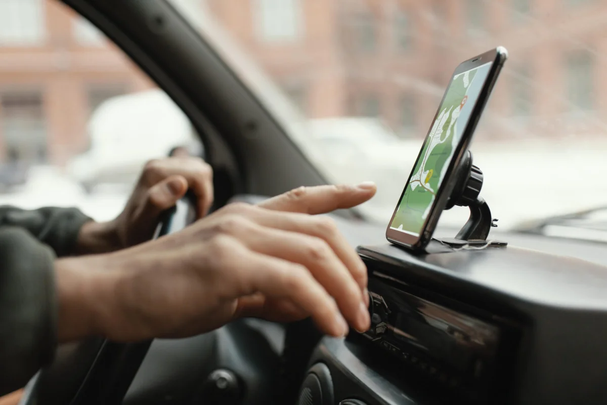 Pessoa com celular próximo a um carro.