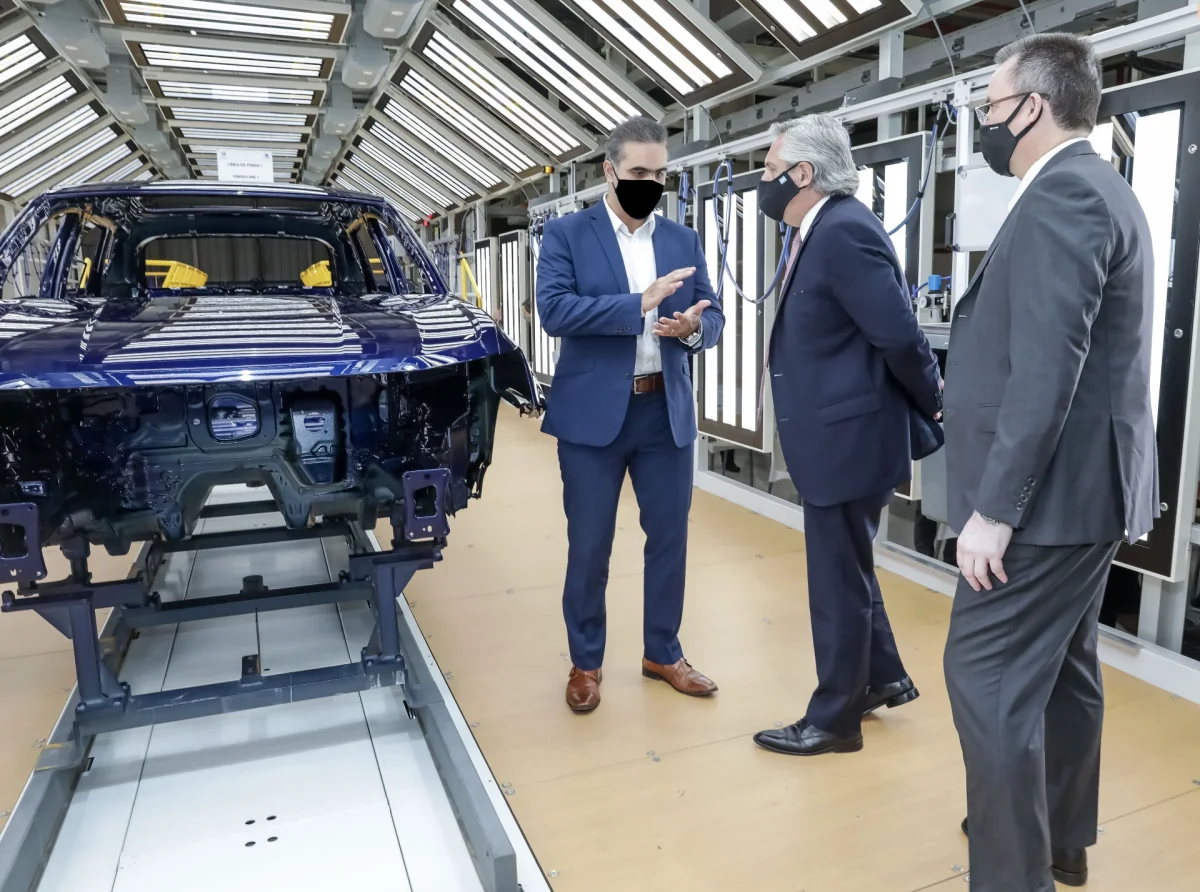 Fábrica de automóveis com várias pessoas observando