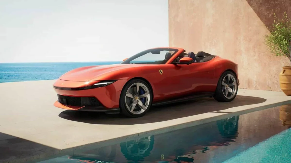 Ferrari vermelha conversível ao lado de piscina.