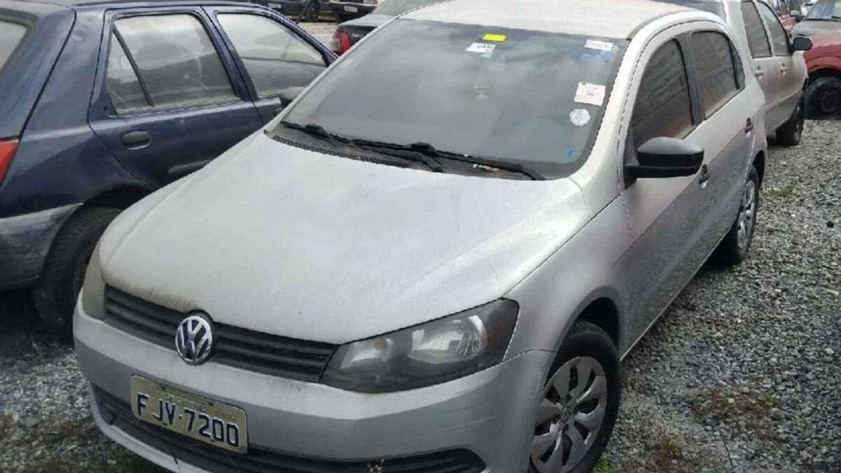 Carro Volkswagen Gol cinza em pátio.