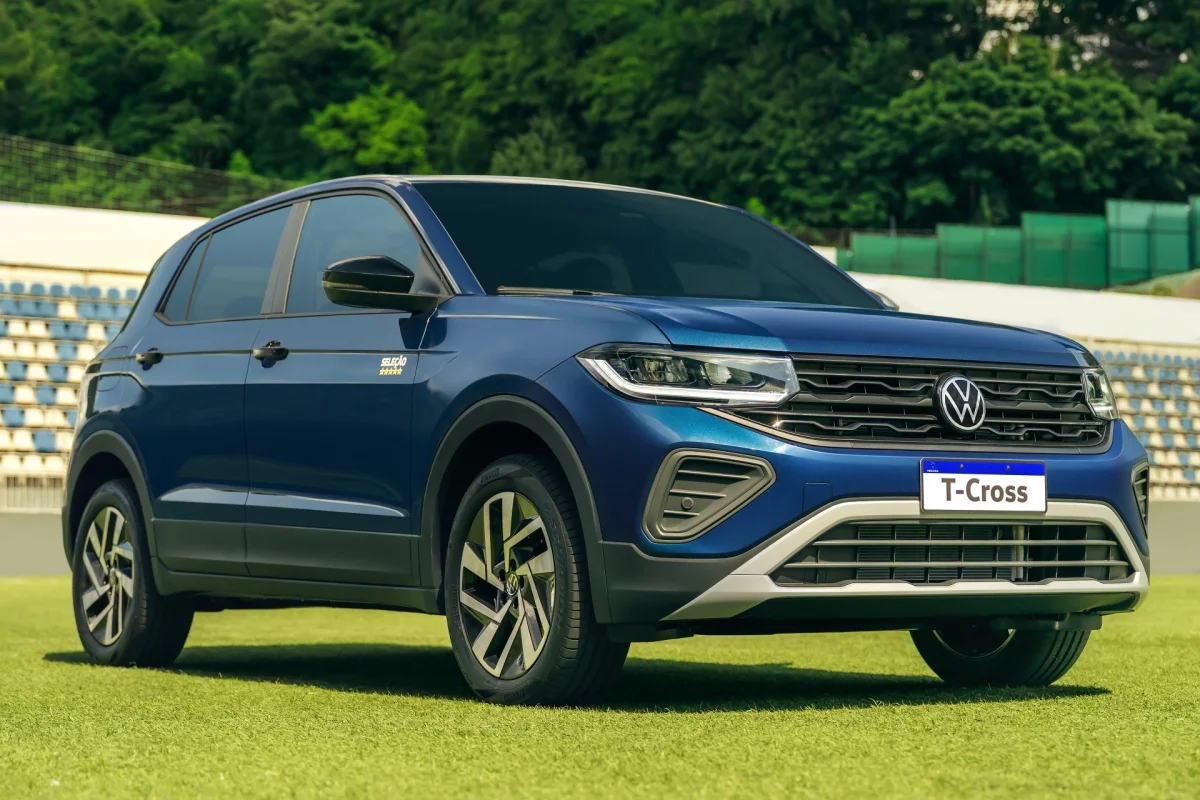 Vista lateral do Volkswagen T-Cross Sele&ccedil;&atilde;o 2026 em um est&aacute;dio.