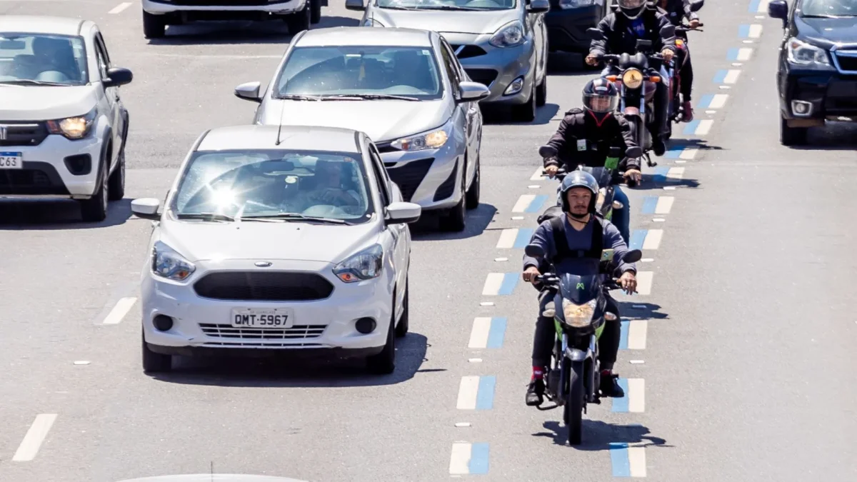 Veículos em pista com faixa azul sinalizada.