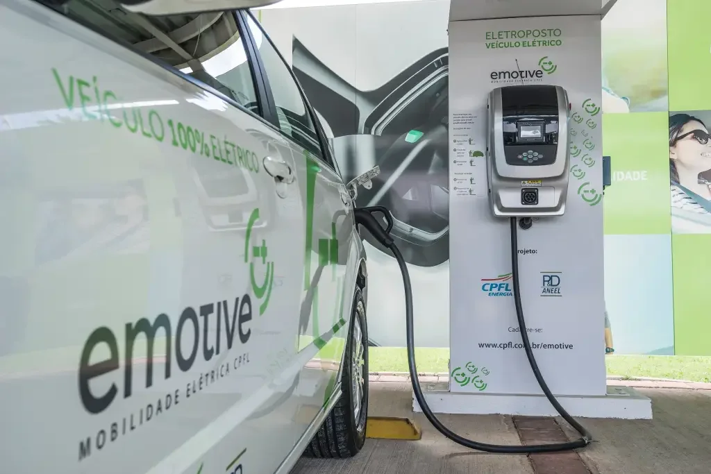 Carro elétrico plugado em estação de recarga.