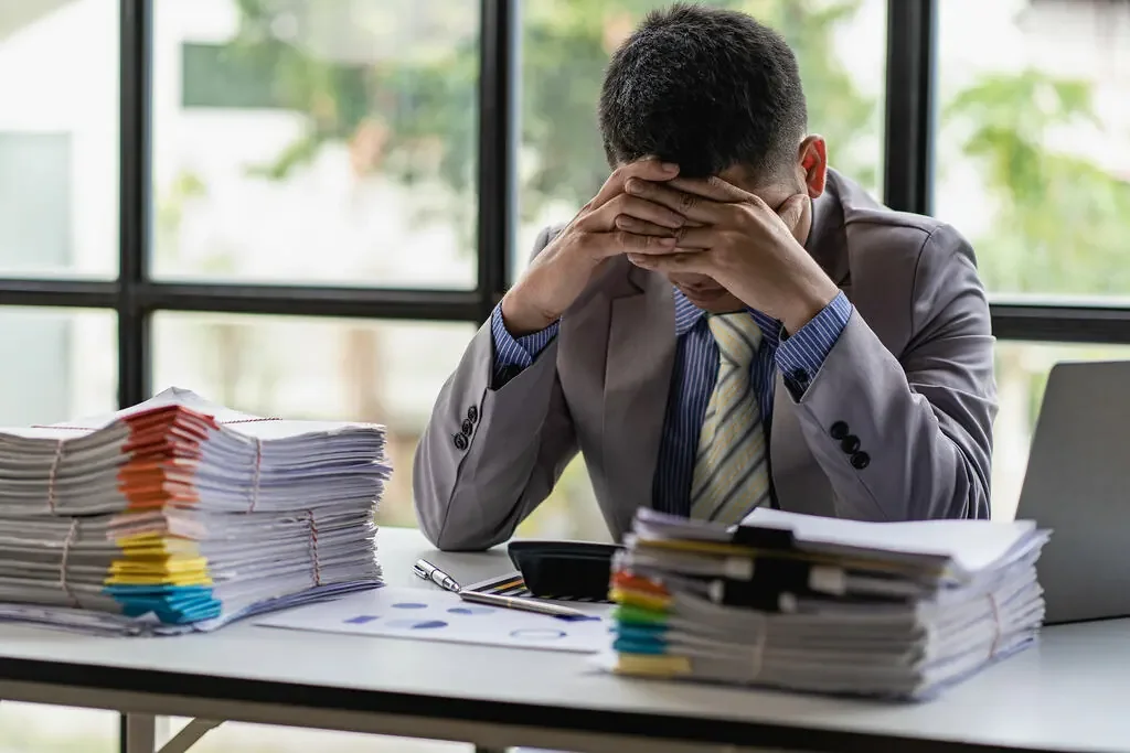 Homem frustrado com pilhas de documentos