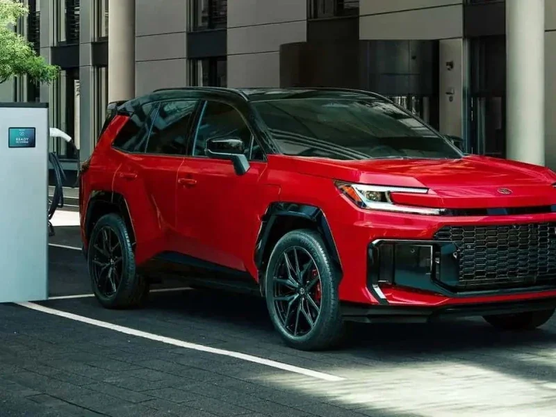Toyota RAV4 vermelho parado próximo a uma estação de carregamento.