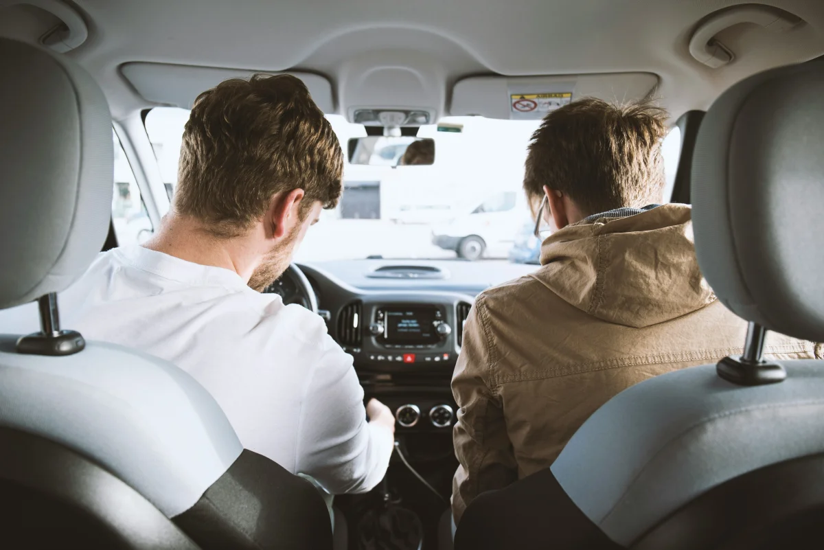 Duas pessoas dentro de um carro, visualizando o painel.