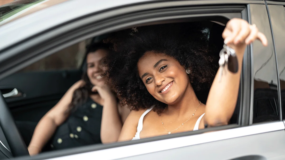 Jovem segurando as chaves de um carro com um sorriso.